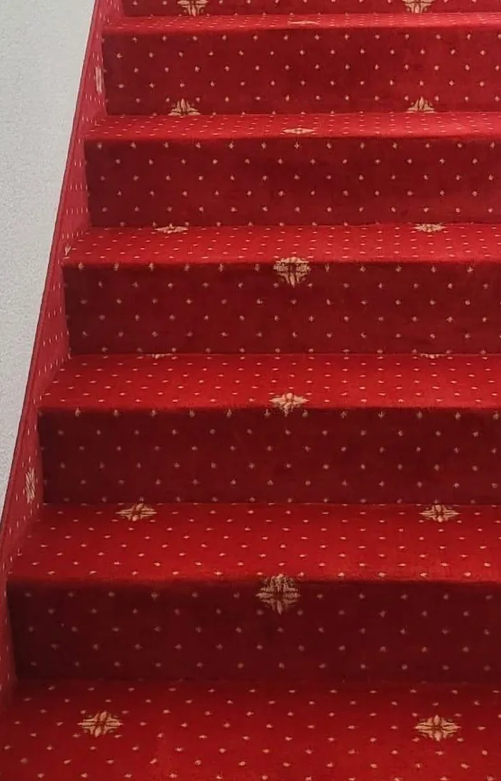 Derselbe Stiegenteppich nach der Tiefenreinigung, Farbe wieder kräftig rot