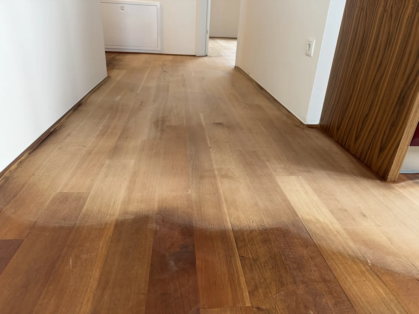 Alter Holzboden mit dunklen Wasserflecken und abgenutzten Laufwegen vor der Aufbereitung