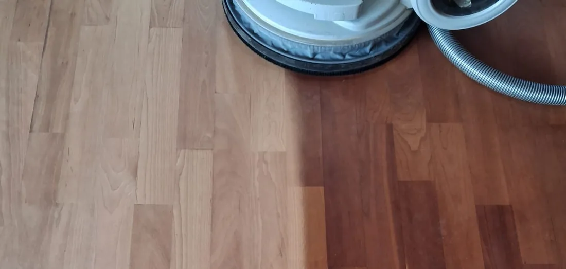 Parkettboden unter der Schleifmaschine: links die frisch geschliffene helle Fläche, rechts der alte dunkle Boden